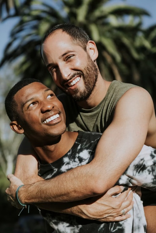 Two people smiling as they embrace outdoors